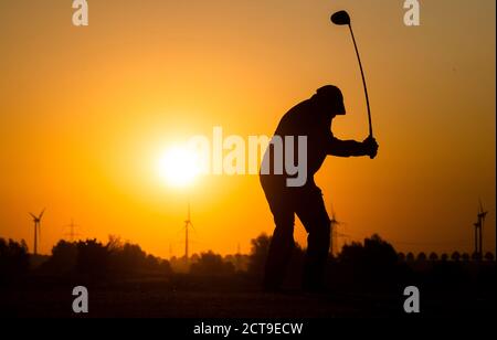 Laatzen, Deutschland. September 2020. Auf der Driving Range auf dem Golfplatz Gleidingen in der Region Hannover trifft ein Mann Golfbälle, wenn die Sonne am Horizont aufgeht. Kredit: Julian Stratenschulte/dpa/Alamy Live Nachrichten Stockfoto