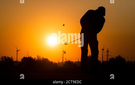 Laatzen, Deutschland. September 2020. Auf der Driving Range auf dem Golfplatz Gleidingen in der Region Hannover trifft ein Mann Golfbälle, wenn die Sonne am Horizont aufgeht. Kredit: Julian Stratenschulte/dpa/Alamy Live Nachrichten Stockfoto