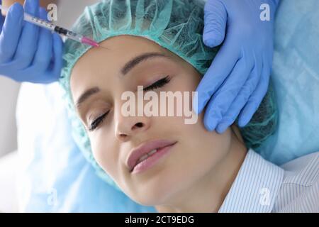 Arzt Kosmetikerin injiziert Injektion in die Stirn der jungen Frau in Schönheitssalon Stockfoto