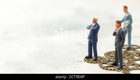 Getriebekonzept im Geschäft. Das Business-Team als einziger Getriebemechanismus im Unternehmen. Geschäftsleute im Anzug stehen auf Zahnrädern. Stockfoto