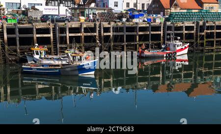 Spiegelungen von Fischerbooten, die im Hafen von Scarborough festgemacht sind, gesehen im September 2020 bei Ebbe. Stockfoto