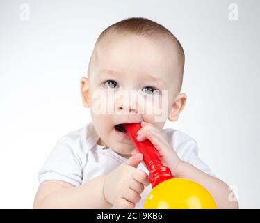 Foto eines elf Monate alten Babys mit Rassel im Mund Stockfoto