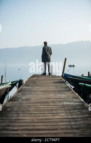 Mann auf Holzsteg am See ansehen Stockfoto