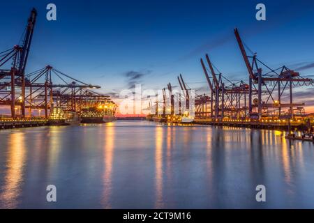 Deutschland, Hamburg, Hamburger Hafen, Containerterminal, Containerkrane und Containerschiffe am Abend Stockfoto