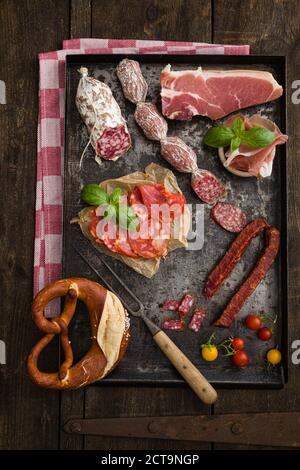 Gemischte Aufschnitt-Platte mit Cocktailtomaten, eine Brezel, frischem Basilikum, Chorizo, Salami, Schinken Stockfoto