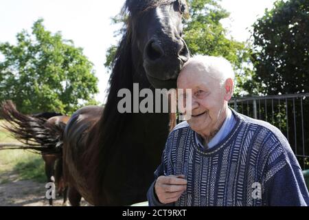 Deutschland, Senior Mann stehend neben Pferd, Lächeln Stockfoto