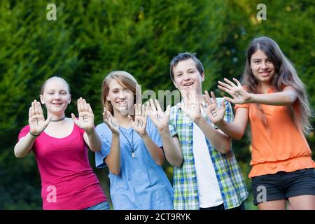 Drei Mädchen und ein Junge, die zusammen die Wort Teenager auf ihre Handflächen zeigen Stockfoto