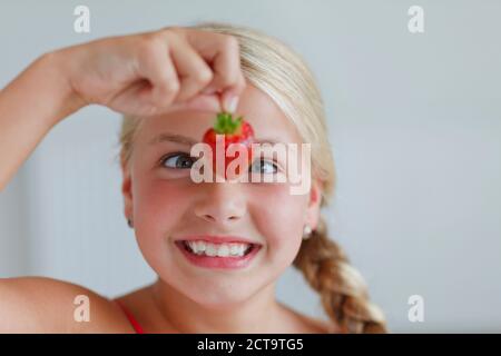 Lächelnde blonde Mädchen Blick auf Erdbeere Stockfoto