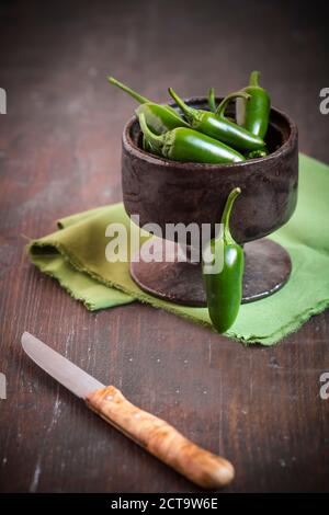 Grüne Jalapeno-Chilis (Capsicum Annuum) in eine Schüssel geben, Studio gedreht Stockfoto