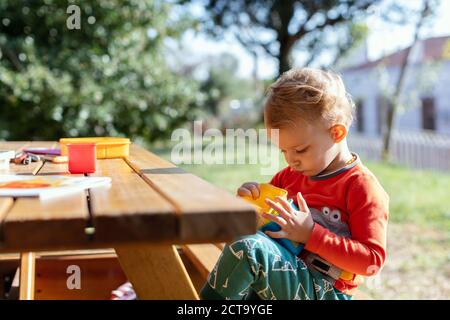 Ein Baby Junge spielt pädagogische Würfel Spielzeug im Garten Stockfoto