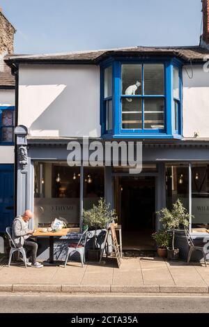 Ein Kunde sitzt an einem Pflastertisch an einem sonnigen Tag außerhalb des Wild Thyme Restaurants, in der Hauptstraße der kleinen Stadt Presteigne, Powys, Wales, Großbritannien Stockfoto