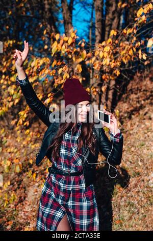 Schönes Mädchen hört Musik auf dem Smartphone und tanzen in Herbstpark Stockfoto