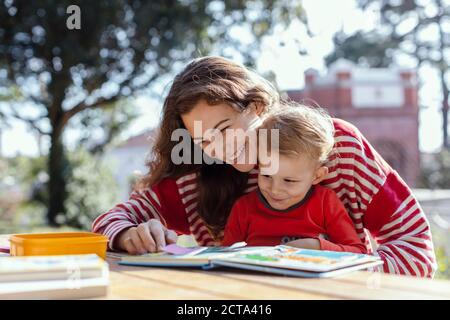 Glückliche Mutter und Kleinkind Lesung Lift-the-Flap Kinderbuch in der Garten Stockfoto