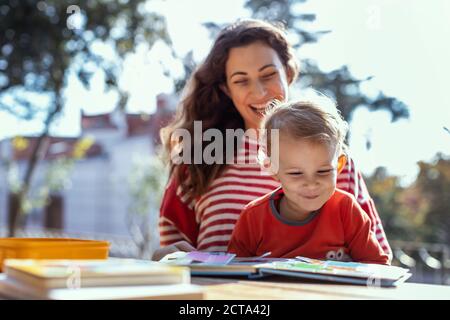 Glückliche Mutter und Kleinkind Lesung Lift-the-Flap Kinderbuch in der Garten Stockfoto