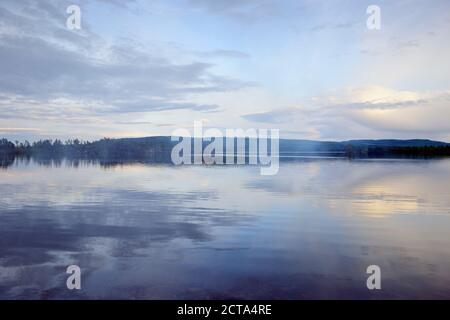 Schweden, Stroemsund, Sonnenuntergang an einem See und Rauch von einem Lagerfeuer Stockfoto