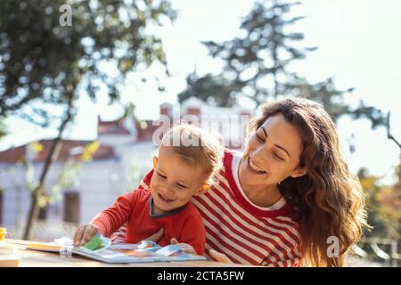 Glückliche Mutter und Kleinkind Lesung Lift-the-Flap Kinderbuch in der Garten Stockfoto