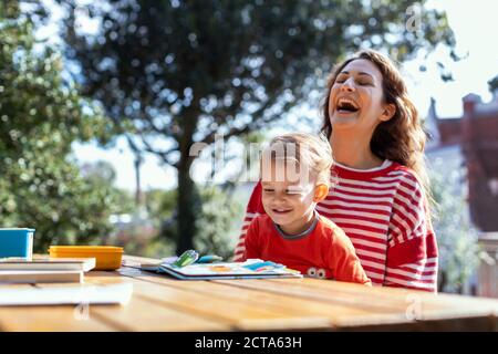 Glückliche Mutter und Kleinkind Lesung Lift-the-Flap Kinderbuch in der Garten Stockfoto