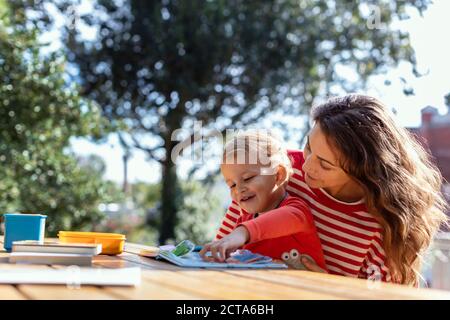 Glückliche Mutter und Kleinkind Lesung Lift-the-Flap Kinderbuch in der Garten