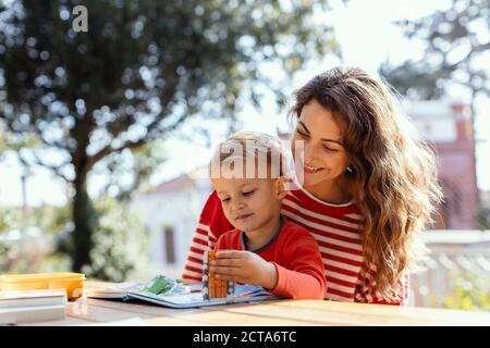 Glückliche Mutter und Kleinkind Lesung Lift-the-Flap Kinderbuch in der Garten Stockfoto