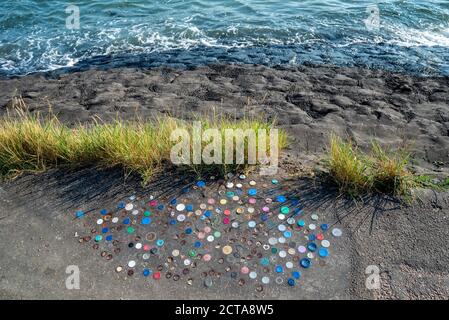 Plastikflaschen-Tops wurden in Chalkwell, Southend on Sea, Essex, Großbritannien, in die Teerschicht der Ufermauer geschoben. Schlackenweg an der Themse Mündung mit Flaschenverschlüssen Stockfoto