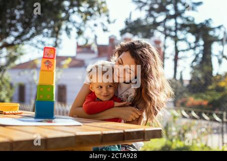 Mutter und Sohn Kuscheln und spielen mit pädagogischen Würfel Spielzeug Im Garten Stockfoto