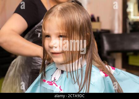 Schöne kleine rothaarige Mädchen im Friseur Shop.Hair Cutting Prozess. Stockfoto