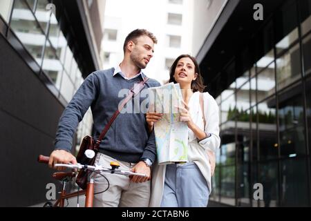 Fröhliche lächelnde Frau und Mann lieben es, mit Karte in der Stadt zu gehen Stockfoto