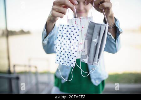 Junge hübsche Frau mit verschiedenen selbstgemachten Schutzmasken gegen Corona, Covid-19 Stockfoto