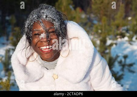 Hübsche afroamerikanische Frau mit Schnee im Gesicht lächelt aus nächster Nähe Stockfoto