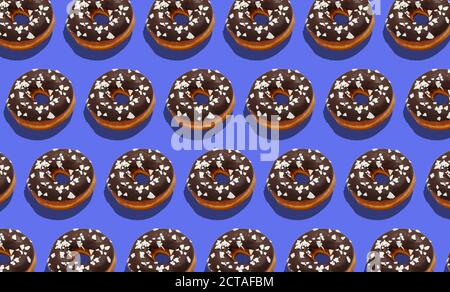 Ungesunde Süßigkeiten und leckere Fast Food für Kunden. Donuts mit Schokolade und weißer Krume auf violettem Hintergrund Stockfoto