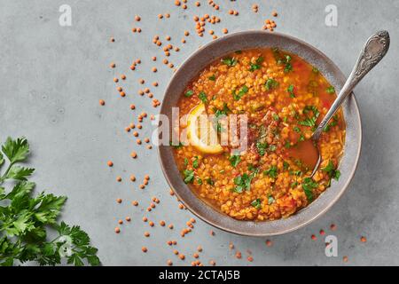 Rote Linsen Tomatensuppe mit Petersilie und Zitrone in grauem Teller auf Beton Tischplatte. Vegetarisches Gericht. Speicherplatz kopieren Stockfoto