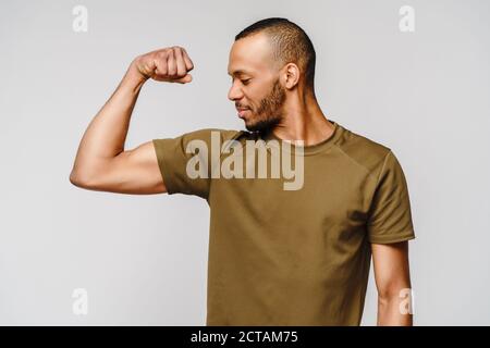 Nahaufnahme Porträt eines glücklichen afroamerikanischen Mannes trägt t-Shirt Biegen Bizep Arm Muskel Stockfoto