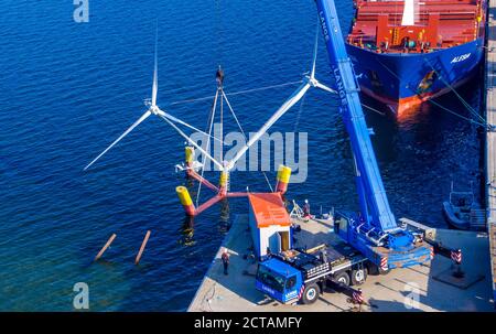 16. September 2020, Mecklenburg-Vorpommern, Vierow: Ein Kran hebt ein Modell einer Anlage mit schwimmenden Windkraftanlagen im Hafen ins Wasser. (Luftaufnahme mit Drohne) die Testanlage ist im Greifswalder Bodden verankert. Das Energieunternehmen EnBW und der Schleswig-holsteinische Windturbinenhersteller Aerodyn Engineering wollen nun Nezzy2 im Meer mit Wellen testen. Das Forschungsprojekt umfasst eine neue Offshore-Technologie, in der die Windenergieanlagen auf dem Wasser schwimmen. Bislang sind Offshore-Turbinen fest auf Stahlrahmen im Meeresboden verankert. Die Modellanlage ist mit t ausgestattet Stockfoto