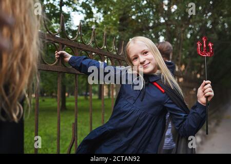 Portrait von blonden Mädchen in Halloween-Kostüm gekleidet halten auf Zaun beim Spielen mit Freunden im Freien, kopieren Raum Stockfoto