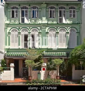Restaurierte grüne Peranakan-Geschäftshäuser mit weißen Holzfensterläden in einem Naturschutzgebiet in Chinatown in Penang, Malaysia. Stockfoto