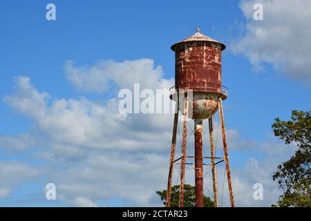 Ein rostiger Wasserturm mit abbläternder Farbe gegen einen teilweise bewölkten Himmel. Stockfoto