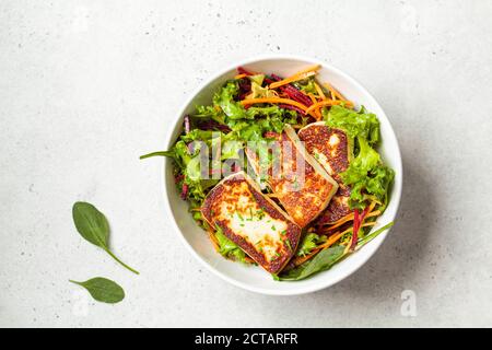 Grüner Salat mit gegrilltem Halloumi-Käse, Rüben und Karotten in einer weißen Schüssel. Diät-Food-Konzept. Stockfoto