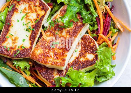 Grüner Salat mit gegrilltem Halloumi-Käse, Rüben und Karotten in einer weißen Schüssel. Diät-Food-Konzept. Stockfoto