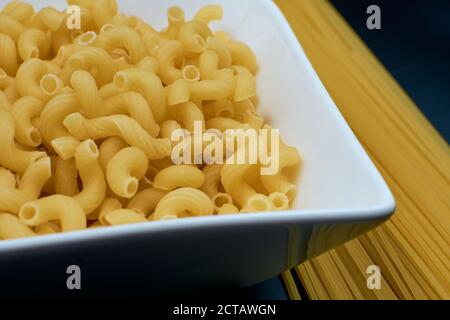 Kleine Pasta in Form eines Frühlings in einem weißen Teller Spaghetti Pasta auf einem dunklen Hintergrund. Nahaufnahme. Stockfoto