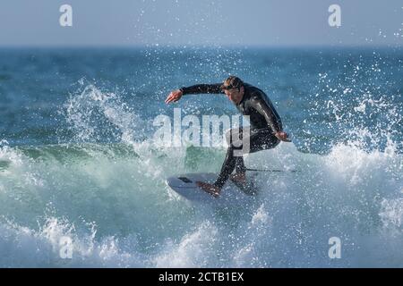 Spektakuläre Surfaktion als reifer Surfer reitet eine Welle am Fistral in Newquay in Cornwall. Stockfoto