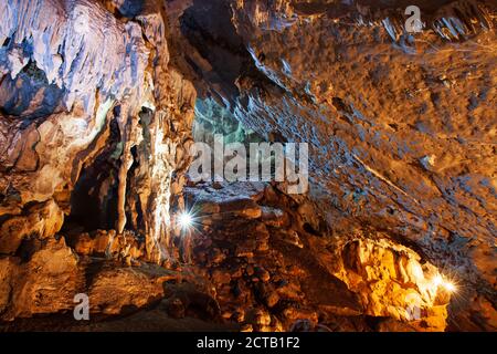 Erkunden mystische Kalksteinhöhle mit Fackel, magische Form und Textur von Stalaktiten und Stalagmiten in der großen Höhle. Nam Nao, Thailand. Stockfoto