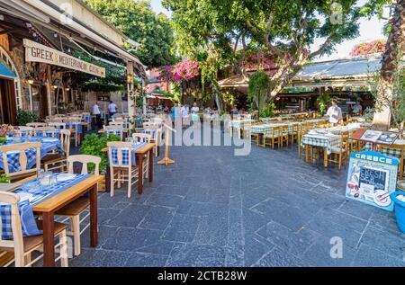 Tische und Stühle der griechischen Taverne säumen den Fußweg in der Altstadt von Rhodos, Dodekanes, Griechenland Stockfoto