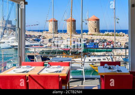 Blick auf die Windmühle von einem schwimmenden Restaurant im Mandraki Hafen auf der Insel Rhodos, Dodekanes, Griechenland Stockfoto