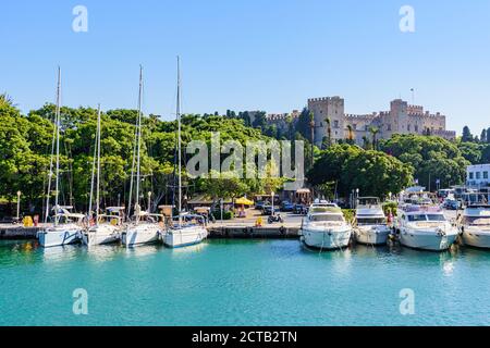 Jachten und Boote, die im Mandraki Hafen unter dem alten mittelalterlichen Palast der Großmeister, Rhodos Stadt, Rhodos Insel, Griechenland, festgemacht sind Stockfoto