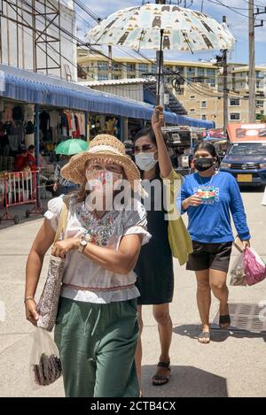 Thailand Straßenszene mit Frau trägt Gesichtsmasken und Abschirmung Unter einem Sonnenschirm Stockfoto
