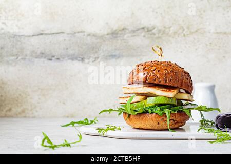Gebratener Halloumi-Burger mit Avocado-Keilen und Rucola. Vegetarisches Konzept. Stockfoto