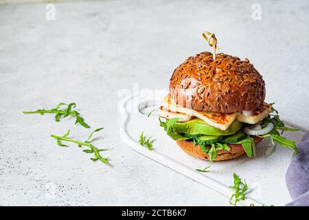 Gebratener Halloumi-Burger mit Avocado-Keilen und Rucola. Vegetarisches Konzept. Stockfoto