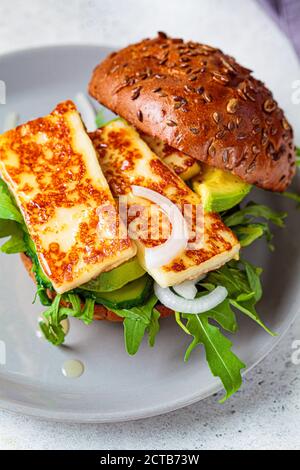 Gebratener Halloumi-Burger mit Avocado-Keilen und Rucola. Vegetarisches Konzept. Stockfoto