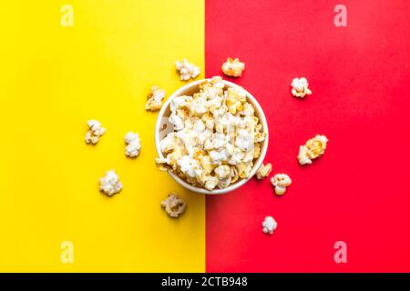 Popcorn in rot-weißem Karton auf rot und Gelber Hintergrund Draufsicht Flat Lay Copy Space Stockfoto