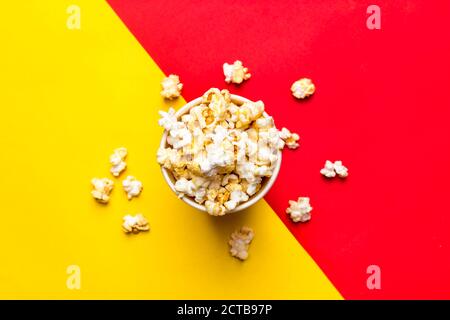 Popcorn in rot-weißem Karton auf rot und Gelber Hintergrund Draufsicht Flat Lay Copy Space Stockfoto